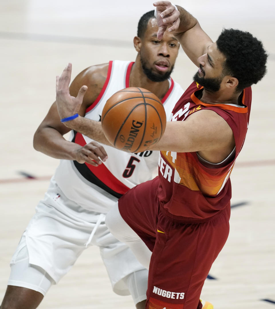 Denver Nuggets guard Jamal Murray, front, loses control of the ball as he drives the lane while Portland Trail Blazers guard Rodney Hood defends in the first half of an NBA basketball game on Tuesday, Feb. 23, 2021, in Denver. (AP Photo/David Zalubowski)