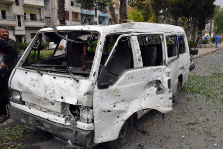 Men inspect a damaged vehicle after an explosion in the al-Zahraa neighbourhood of Homs city in this handout picture provided by SANA on May 23, 2017, Syria. SANA/Handout via REUTERS