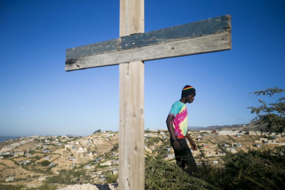 A resident walks past a cross during a memorial service honoring the victims of the 2010 earthquake, at Titanyen, a mass burial site north of Port-au-Prince, Haiti, Sunday, Jan. 12, 2020. Sunday marks the 10th anniversary of the devastating 7.0 magnitude earthquake that destroyed an estimated 100,000 homes across the capital and southern Haiti, including some of the country's most iconic structures. (AP Photo/Dieu Nalio Chery)