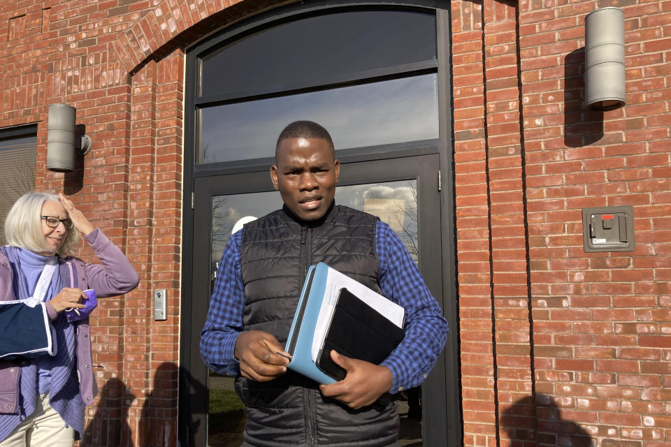 Ugandan refugee Steven Tendo, center, steps out of a federal immigration office, in St. Albans, Vt., Tuesday, Nov. 15, 2022, after learning that his deportation has been delayed for a year. Tendo is an Ugandan activist who says he fears for his life if he were to be deported to his home country. (AP Photo/Lisa Rathke)