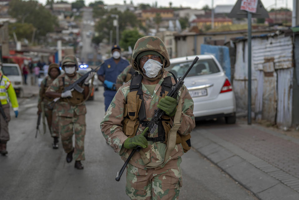 South African National Defense Forces patrol the densely populated Alexandra township east of Johannesburg Friday, March 27, 2020. South Africa went into a nationwide lockdown for 21 days in an effort to mitigate the spread to the coronavirus, but in Alexandra, many people were gathering in the streets disregarding the lockdown. The new coronavirus causes mild or moderate symptoms for most people, but for some, especially older adults and people with existing health problems, it can cause more severe illness or death.(AP Photo/Jerome Delay)