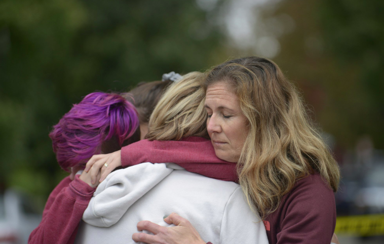 Women outside the synagogue embrace in the wake of the shooting. Source: AP