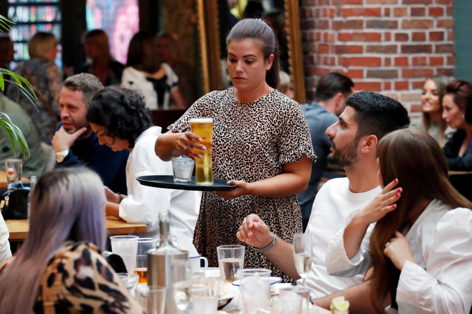 An employee is seen with customers at The Practicioner pub after it reopened following the outbreak of the coronavirus disease (COVID-19), Hertford, Britain, July 4, 2020. / Credit: ANDREW COULDRIDGE / REUTERS