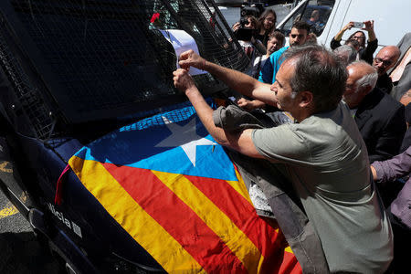 A protestor attaches a ballot paper on a Mossos d'Esquadra's riot van outside the Catalan region's economy ministry building during a raid by Spanish police on several government offices, in Barcelona, Spain, September 20, 2017. REUTERS/Albert Gea