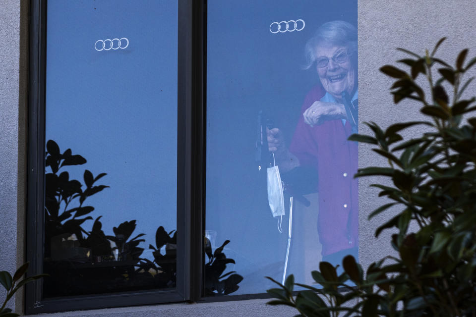 A resident at the Arcare Aged Care facility in Maidstone reacts to media from her window, in Melbourne.