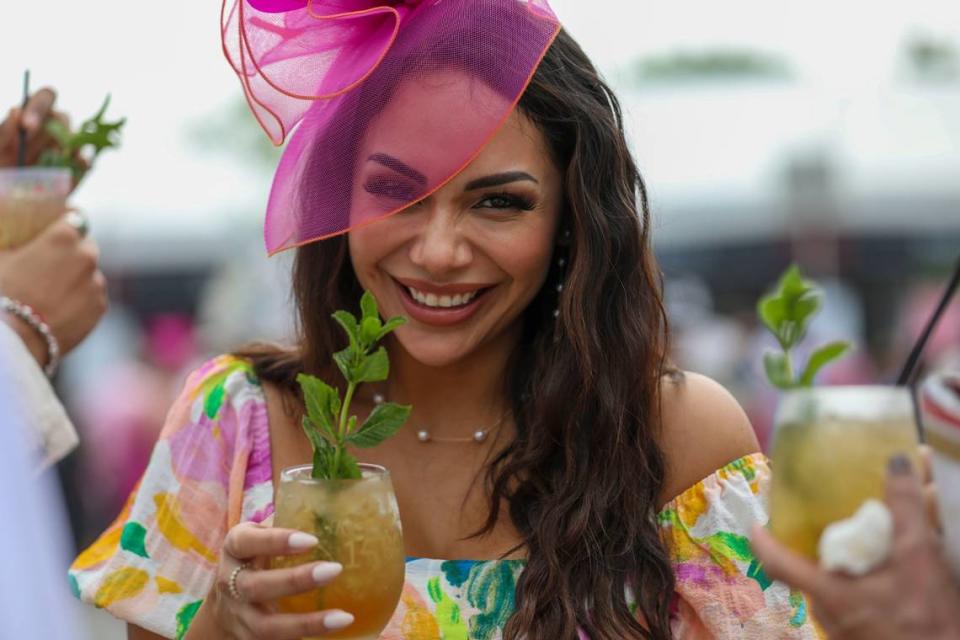 Martha Barreto drinks a mint julep at Churchill Downs on Saturday. She found her fuchsia and orange fascinator online.