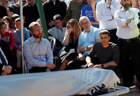 Relatives and friends mourn as they sit next to the body of Israeli rabbi Achiad Ettinger, wrapped in a Jewish prayer shawl, during his funeral, in the Jewish settlement of Eli in the Israeli-occupied West Bank March 18, 2019. REUTERS/Ronen Zvulun