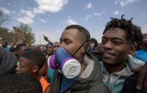 Protesters demonstrate outside a police station at Eldorado Park, Johannesburg, South Africa, Thursday, Aug. 27, 2020. Residents from the township, south of Johannesburg are demanding justice for a teenager shot and killed, allegedly at the hands of police Wednesday. (AP Photo/Themba Hadebe)