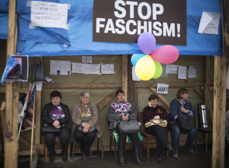 FILE - In this Monday, April 21, 2014 file photo people rest under a tent next to barricades at the Ukrainian regional office of the Security Service in Luhansk, Ukraine. The propaganda assault began during the pro-Western Maidan protests late last year that ousted Ukraine’s pro-Russian president in February: Russian state news media were quick to dismiss the protests as the work of Ukrainian neo-Nazis, a particularly loaded accusation because Ukrainian nationalists collaborating with the Nazis are blamed for horrific reprisal attacks during World War II. (AP Photo/Alexander Zemlianichenko, file)