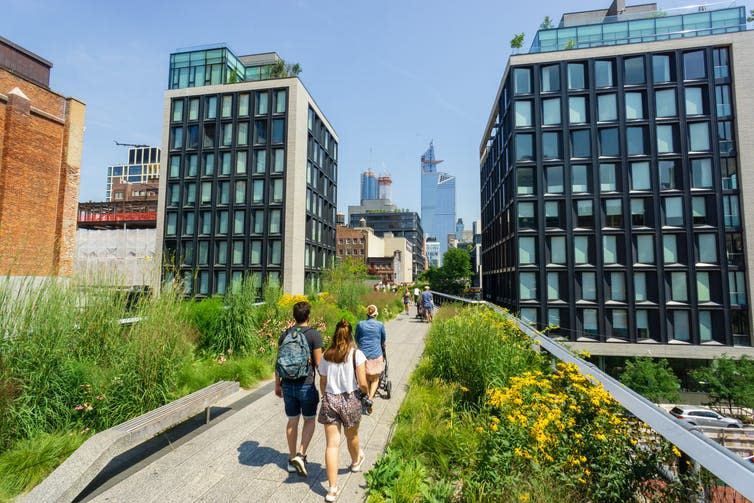 People walk through park between tall buildings