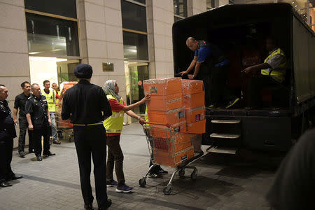 A Malaysian police officer pushes a trolley during a raid of three apartments in a condominum owned by former Malaysian prime minister Najib Razak's family, in Kuala Lumpur. Ariffin Jamar/The Straits Times via REUTERS