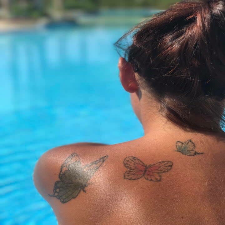 Tattoos of butterflies on a woman's shoulder.