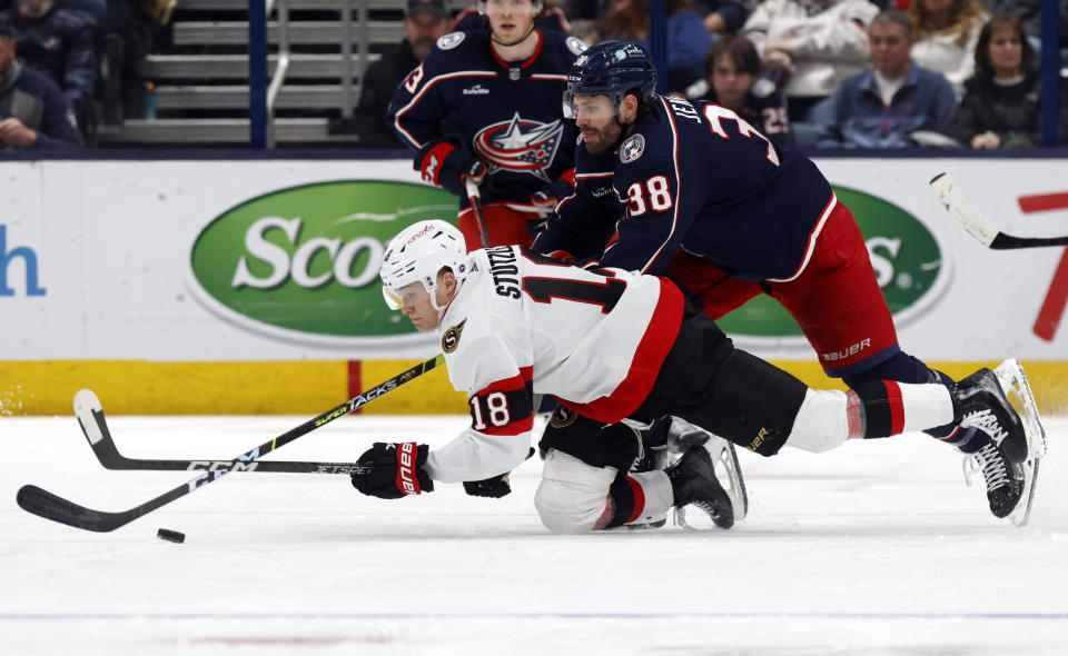 Columbus Blue Jackets forward Boone Jenner, right, reaches for the puck behind Ottawa Senators forward Tim Stutzle during the second period of an NHL hockey game in Columbus, Ohio, Sunday, April 2, 2023. (AP Photo/Paul Vernon)