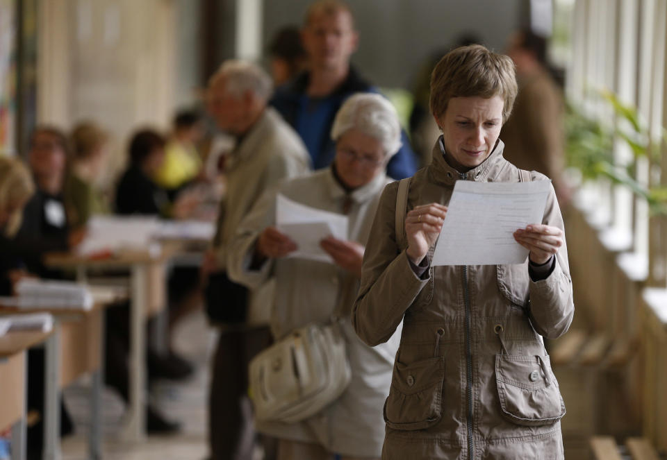 A Lithuanian woman reads a ballot paper at a polling station during the first round of voting in presidential elections in Vilnius, Lithuania, Sunday, May 11, 2014. Polls opened Sunday for the presidential election in Lithuania, where tough-talking incumbent Dalia Grybauskaite is widely expected to be re-elected for a second term. (AP Photo/Mindaugas Kulbis)