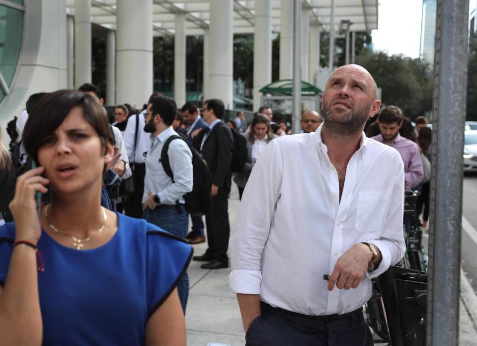 Nicolas Jimenez (right) stands outside a Miami office building after he and others were evacuated after a magnitude 7.7 earthquake that struck between Cuba and Jamaica rattled downtown Miami.