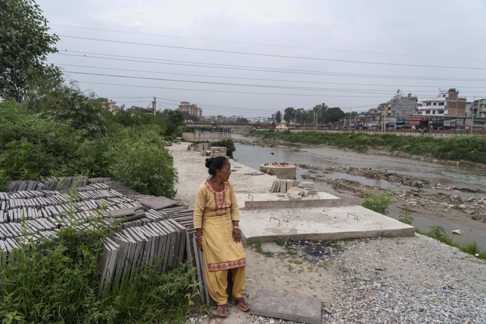 Mithu Lama, de 59 años, descansa cerca de su casa en la orilla del río Bagmati en Katmandú, Nepal, el miércoles 1 de junio de 2022. Nacida y criada junto al Bagmati, Lama recuerda haber usado sus aguas para cocinar, bañarse, lavar e incluso beber. Hoy eso se siente como un sueño lejano, frustrado por décadas de arrojar desechos humanos y basura, y uno que no espera que se realice pronto. (AP Foto/Niranjan Shrestha)