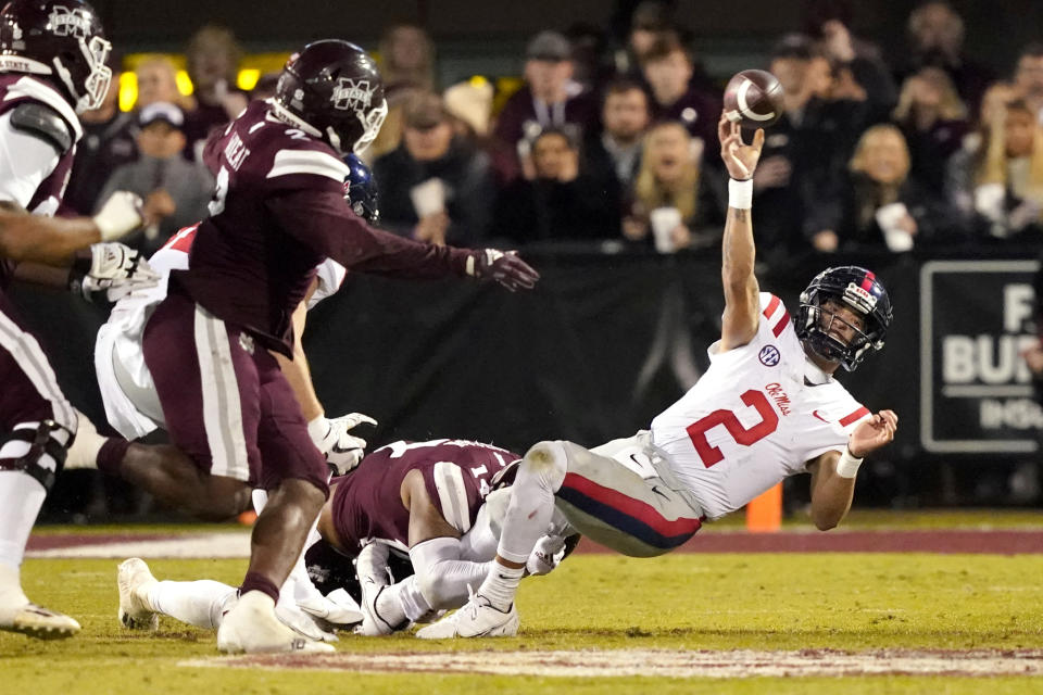 Mississippi quarterback Matt Corral (2) attempts to pass as he is tackled by Mississippi State's Nathaniel Watson during the first half of an NCAA college football game Thursday, Nov. 25, 2021, in Starkville, Miss. (AP Photo/Rogelio V. Solis)