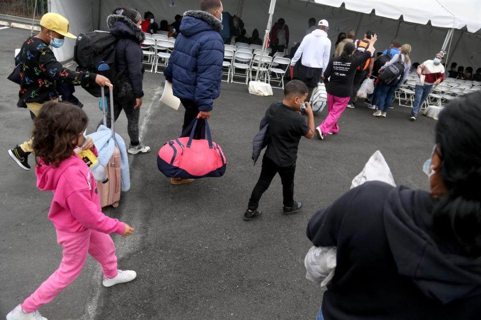 Migrants arrive by bus carrying their belongings to the SDRRN Migrants Shelter