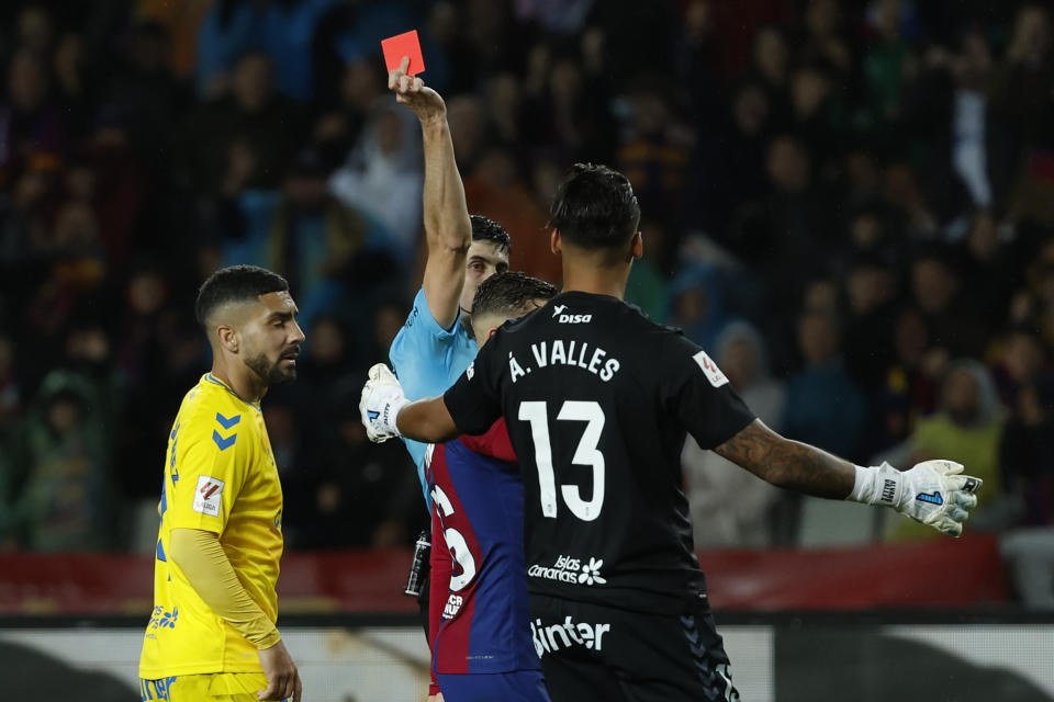 Referee Mateo Busquets Ferrer, background, shows a red card to Las Palmas' goalkeeper Alvaro Valles, right, during a Spanish La Liga soccer match between Barcelona and Las Palmas at the Olimpic Lluis Companys stadium in Barcelona, Spain, Saturday, March 30, 2024. (AP Photo/Joan Monfort)