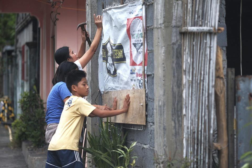 Unas personas refuerzan el exterior de su casa en preparación por la llegada de un tifón en Legazpi, provincia de Albay, al sureste de Manila, Filipinas, el lunes 2 de diciembre del 2109. (AP Foto)