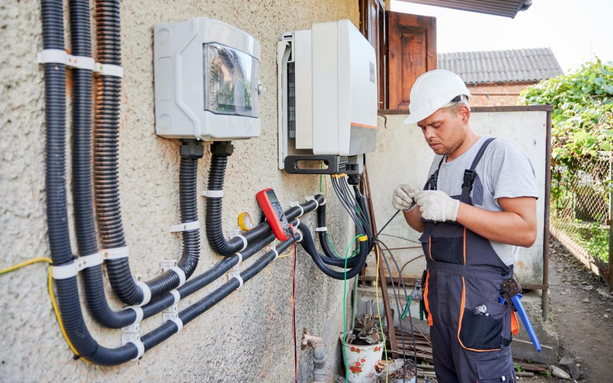 Electrician installing solar panel system on the outside of a house