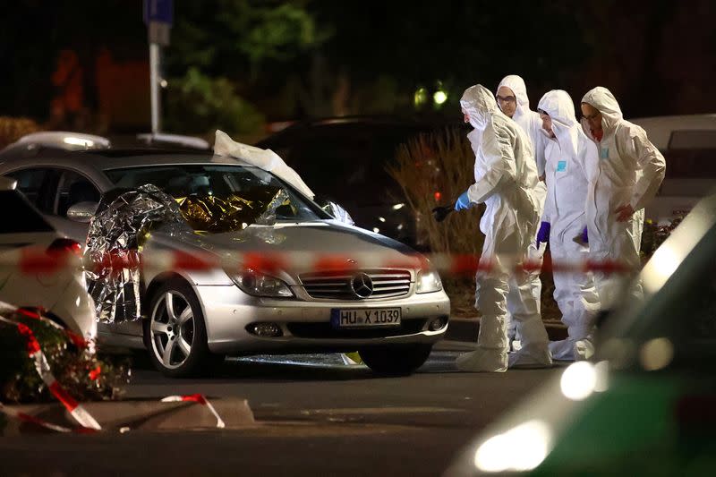 Forensic experts work around a damaged car after a shooting in Hanau near Frankfurt