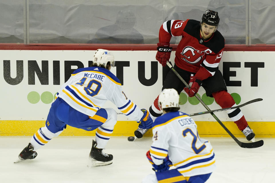 New Jersey Devils center Nico Hischier (13) battles for the puck with Buffalo Sabres defenseman Jake McCabe (19) during the first period of an NHL hockey game, Saturday, Feb. 20, 2021, in Newark, N.J. (AP Photo/John Minchillo)