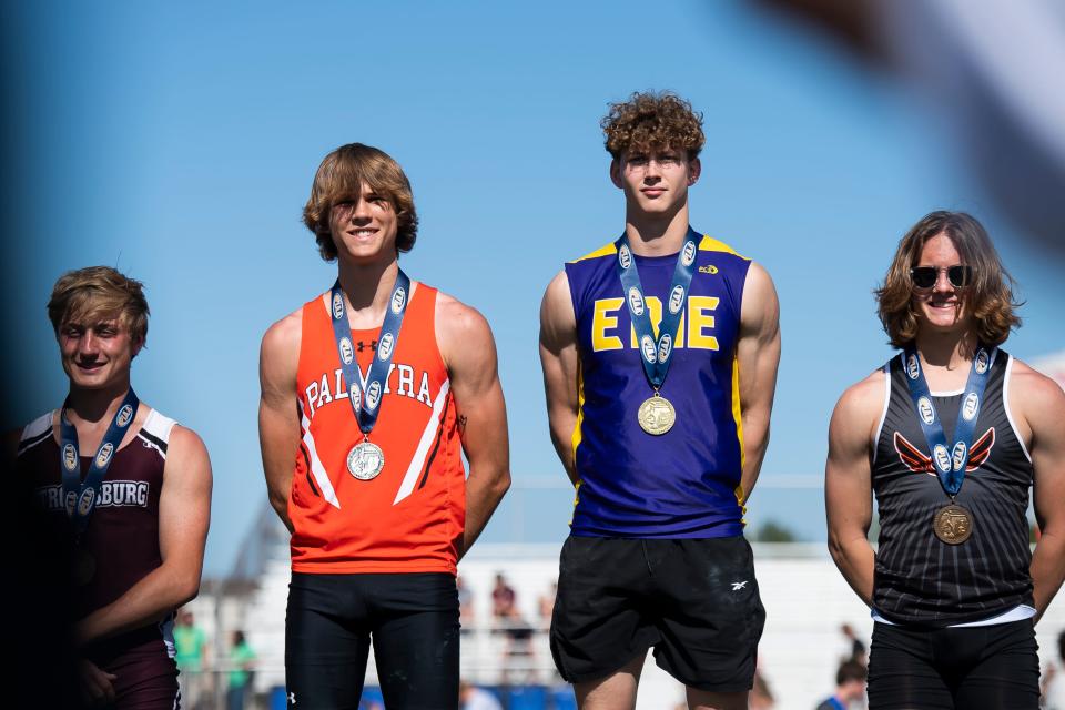 Erie's Bradon Schneider (second from right) and Palmyra's Mason Bucks (third from right) smile on the awards podium after placing first and second, respectively, in the 3A pole vault at the PIAA Track and Field Championships at Shippensburg University Friday, May 26, 2023.