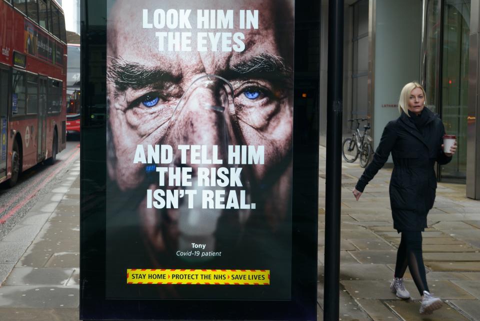 A woman walking past a bus stop with a covid-19 electronic billboard in central London. (Photo by Thomas Krych / SOPA Images/Sipa USA)