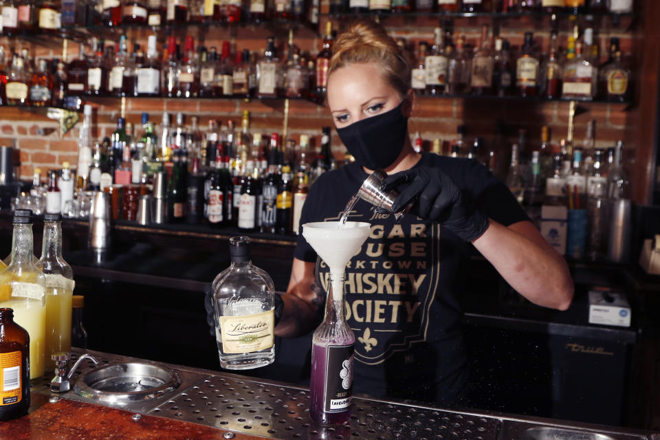 Sugar House bartender Shelby Minnix creates a Lavender Lemonade cocktail in a to-go bottle, Thursday, Aug. 13, 2020, in Detroit. At least 33 states and the District of Columbia are temporarily allowing cocktails to-go during the pandemic, up from around three before the coronavirus struck. Dave Kwiatkowski, who owns the Sugar House was able to reopen July 10 for carryout service. Kwiatkowski normally employs a staff of 16, but for now, it's just him at the door and a bartender making drinks. (AP Photo/Carlos Osorio)