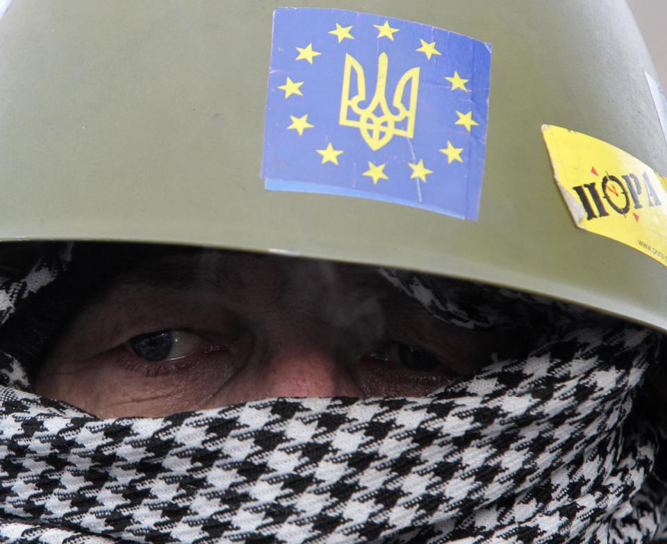 A protester looks at riot police from a barricade in central Kiev, Ukraine, Saturday, Feb. 1, 2014. Ukraine's embattled president Viktor Yanukovych is taking sick leave as the country's political crisis continues without signs of resolution. (AP Photo/Sergei Chuzavkov)