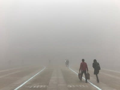 FILE PHOTO: People walk in the smog towards a railway station on a polluted day in Zhengzhou, Henan province, China January 9, 2017. REUTERS/Stringer/File Photo