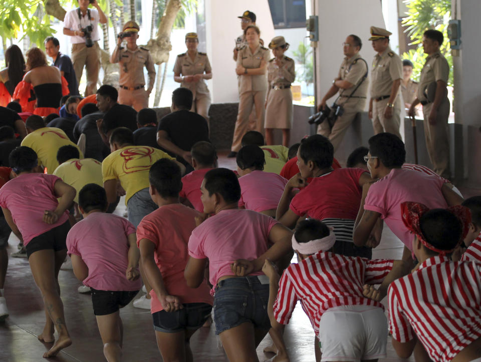 Thai prison officials, background, watch as inmates do the stretching before performing "Gangnam Style" dance during the dancing competition at a prison in Bangkok, Thailand Tuesday, Nov. 27, 2012. The event was held to encourage inmates to do more exercise and coincide with the concert of South Korean rapper PSY's "Gangnam Style" to be held in Bangkok on Wednesday, Nov. 28. (AP Photo/Apichart Weerawong)