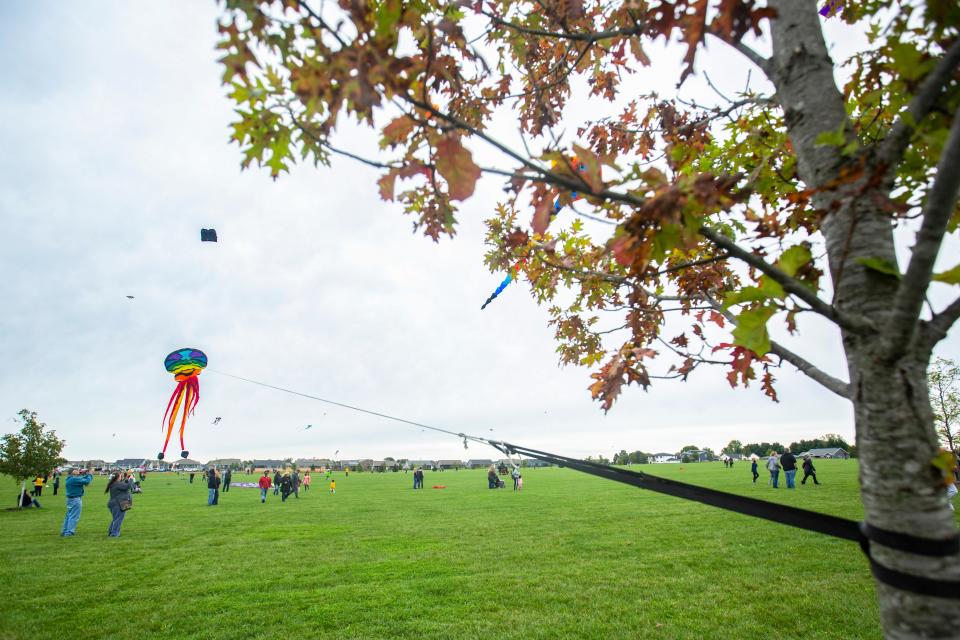 A rainbow colored squid kite floats through the air as spectators take in the sights surrounding them during 'Take Flight!,' an event sponsored by the Eastern Iowa Airport, featuring large character kites from the Great American Kites & Events company, Sunday, Oct., 6, 2019, at Centennial Park in North Liberty, Iowa.
