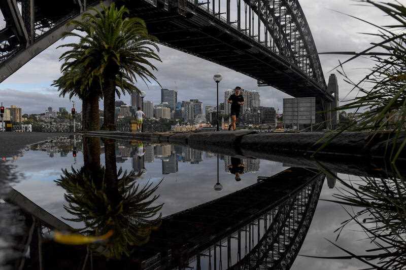 People exercise past the Sydney Harbour Bridge in Sydney.