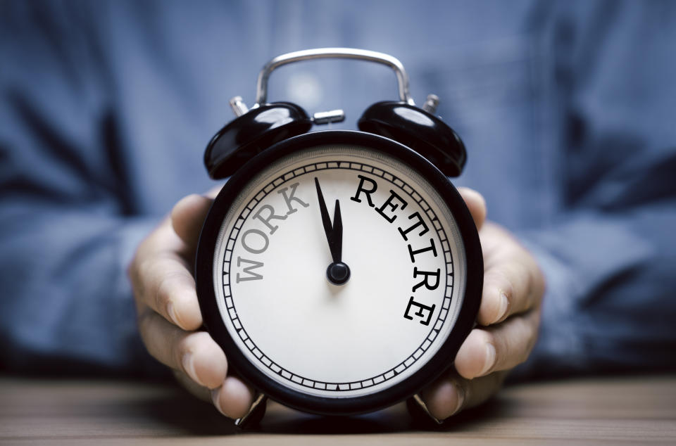 Person holding a clock with "WORK" and "RETIRE" text replacing numbers, symbolizing work-life balance