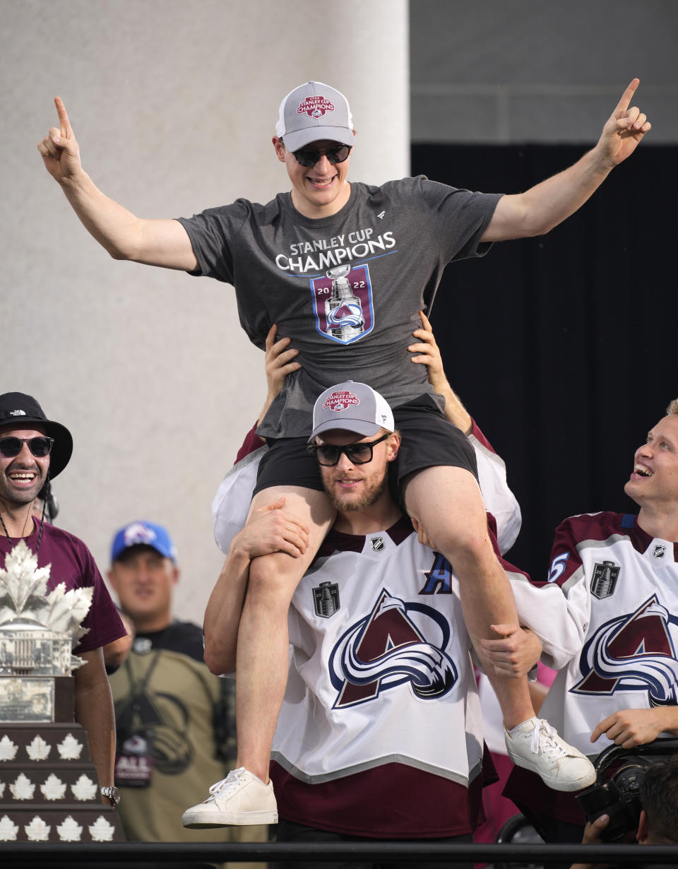 FILE -Colorado Avalanche right wing Mikko Rantanen, center bottom, lifts defenseman Cale Makar, center top, during a rally outside the City/County Building for the NHL hockey champions after a parade through the streets of downtown Denver, Thursday, June 30, 2022. Looking on are center Nazem Kadri, left, and right wing Logan O'Connor. All the Stanley Cup parties and parades are over for the Colorado Avalanche. The shorter-than-most summer has run its fun-loving, Cup-hoisting course and training camp has arrived. It's time to get back to the task of defending the title. (AP Photo/David Zalubowski, File)