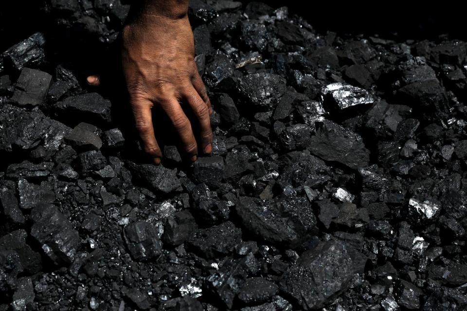 A hand separates pieces of coal.