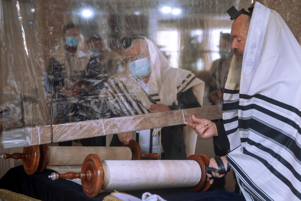 Ultra-Orthodox Jews keep social distancing and wear face masks during a morning prayer next to their houses as synagogues are limited to twenty people during a nationwide three-week lockdown to curb the spread of the coronavirus, in Bnei Brak, Israel, Monday, Sept 21, 2020. (AP Photo/Oded Balilty)