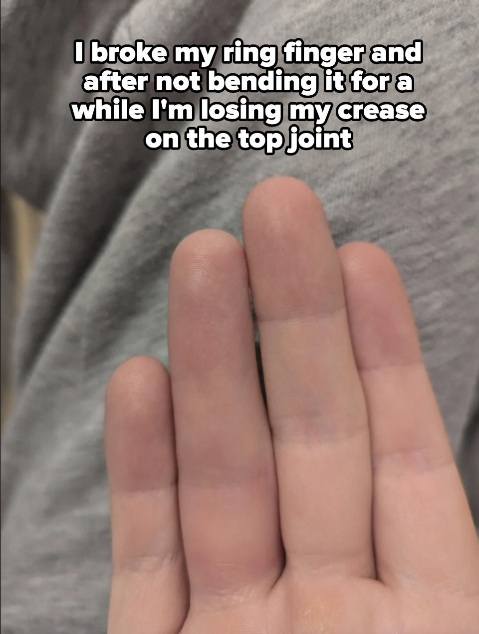 A close-up of fingers held together with a grey fabric backdrop