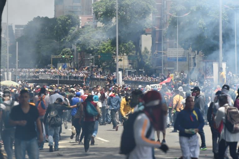 Demonstrators against Nicolas Maduro's government are seen amid a tear gas cloud during clashes with riot police in Caracas on April 8, 2017