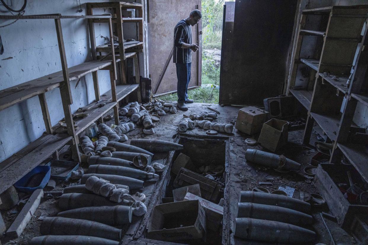 A man stands in the garage with Russian artillery shells in the recently retaken area of Kamyanka, Ukraine, Monday, Sept. 19, 2022. Residents of Izium, a city recaptured in a recent Ukrainian counteroffensive that swept through the Kharkiv region, are emerging from the confusion and trauma of six months of Russian occupation, the brutality of which gained worldwide attention last week after the discovery of one of the world's largest mass grave sites. (AP Photo/Evgeniy Maloletka)