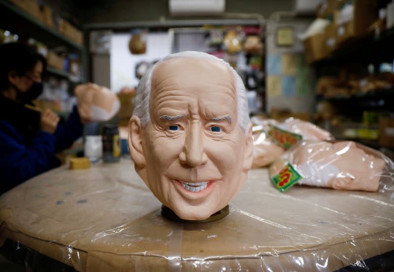 A worker of Ogawa Studios, a mask and toy making company, gives the final touches to a mask depicting U.S. President-elect Joe Biden next to the mask in Saitama, Japan