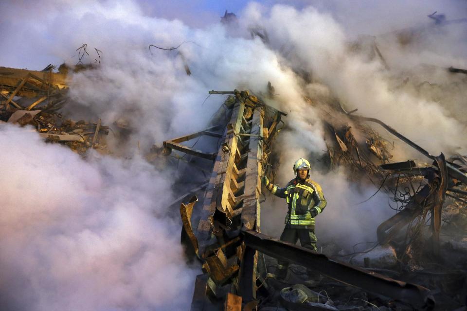 An Iranian firefighter removes debris of the Plasco building which was engulfed by a fire and collapsed on Thursday, in central Tehran, Iran, Saturday, Jan. 21, 2017. Scores of workers and dozens of trucks were searching the ruins Saturday, two days after a historic high-rise building in the heart of Tehran caught fire and later collapsed. (AP Photo/Ebrahim Noroozi)