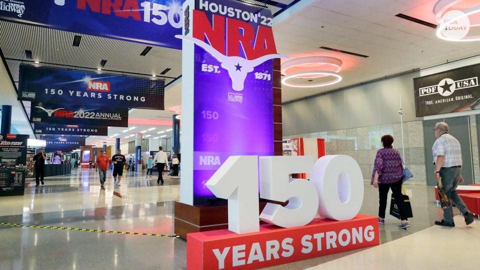 Convention attendants walk past some of the signage in the hallways outside of the exhibit halls at the NRA Annual Meeting held at the George R. Brown Convention Center Thursday, May 26, 2022, in Houston. (AP Photo/Michael Wyke)