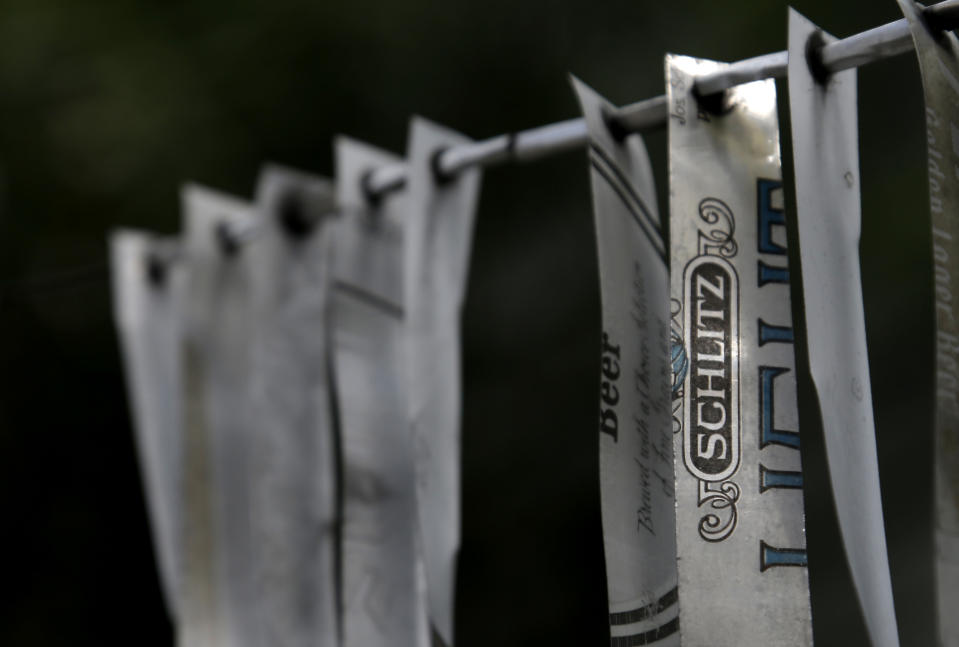 A wind chime made from strips cut from old beer cans hangs outside the beer can house, a Houston landmark, Wednesday, July 10, 2013. Former owner John Milkovisch covered the outside on the house with siding made of cut and flatten beer cans and garlands made from the lids. The Orange Show Center for Visionary Art, a local nonprofit that preserves art installations in the city, bought the property about 10 years ago, restored the house and it opened it to the public. (AP Photo/Pat Sullivan)