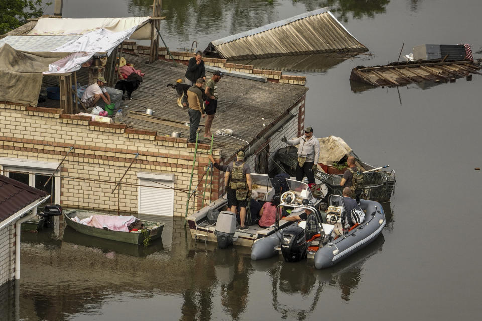 Soldados ucranianos ayudan a residentes a bajar de un tejado para subir a una lancha durante una operación de rescate en un vecindario inundado cerca de Oleshky, Ucrania, el 7 de junio de 2023. En los primeros días tras la rotura de la represa, los rescatistas ucranianos, sorteando a los drones y el peligro de los francotiradores rusos, cruzaron el río Dniéper para evacuar a los civiles de zonas afectadas por las inundaciones en la orilla ocupada por Rusia. (AP Foto)