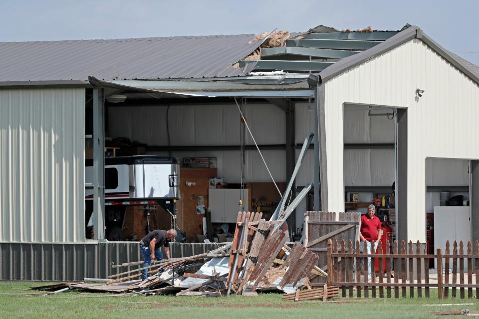 People clean up storm damage to garage near Banner Road and SW 15 in Canadian County on Monday.
