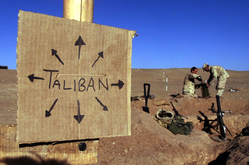 <p>US Marines from Charlie 1/1 of the 15th MEU (Marine Expeditionary Unit) fill sand bags around their light mortar position on the front lines of the US Marine Corps base in southern Afghanistan Dec. 1, 2001 nearby a cardboard sign reminding everyone that the Taliban forces could be anywhere and everywhere. (Photo: Jim Hollander/Reuters) </p>
