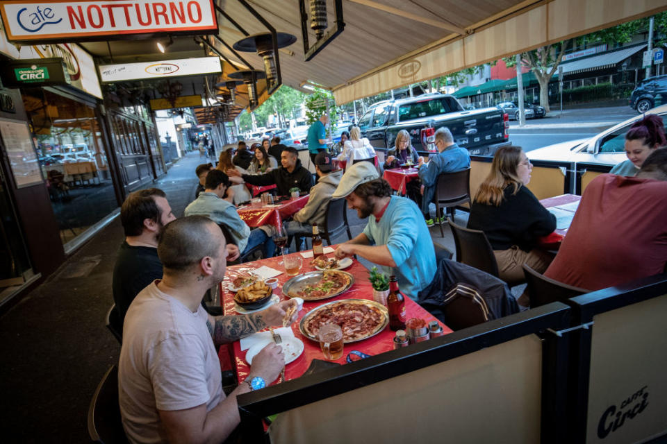 Groups of people dining outdoors on Lygon Street, Carlton.